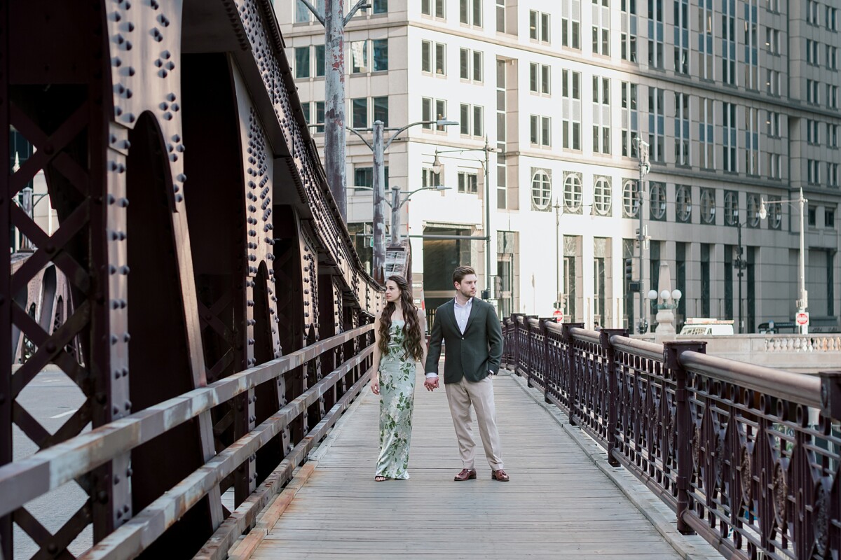 Newly Engaged couple standing on a bridge in downtown Chicago during their Chicago Riverwalk Engagement Photoshoot Downtown Chicago-Photographed by Chicago Wedding Photographer Erica Melissa